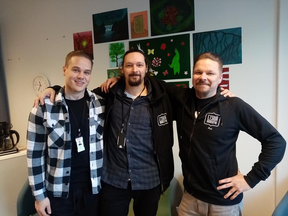 Petja Hamunen, Toni Pakarinen ja Petri Happonen poseeraavat Nuorisoverstaan kuvispajan nuorten tekemien taideteosten edessä. 