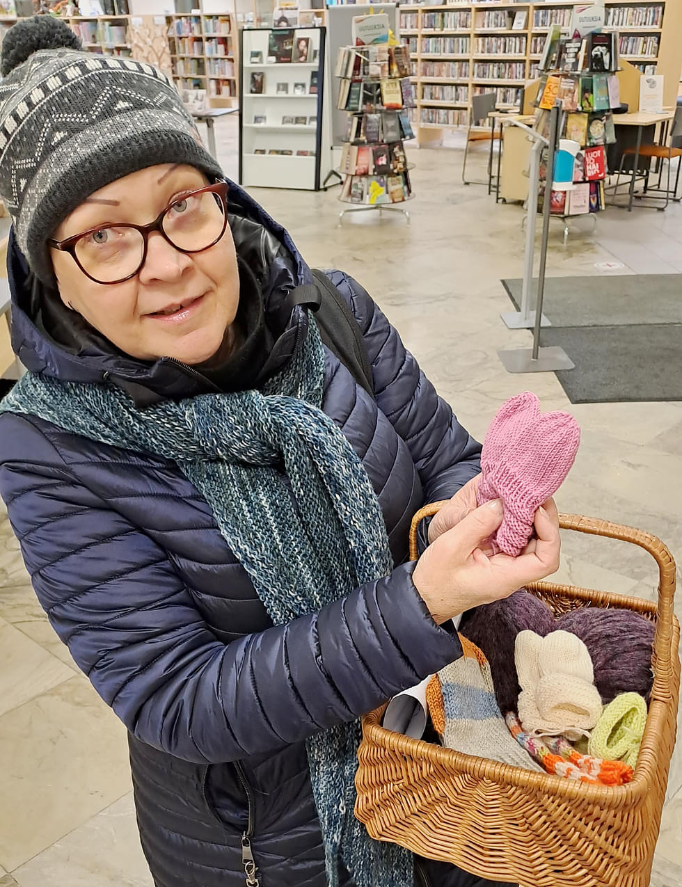 Lea Oravalahti-Pehkonen toi neulomiaan lapasia kirjastoon keskiviikkona. Korissa oli myös lankoja muille, jotka haluavat auttaa neulomalla.