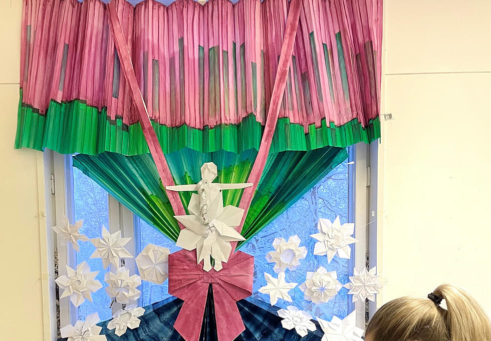 Punaiseksi ja vihreiksi maalatut revontulet hehkuvat Rie Akaguman origami-installaatiossa Heinävaaran vanhan koulun entisen luokkahuoneen ikkunassa. 