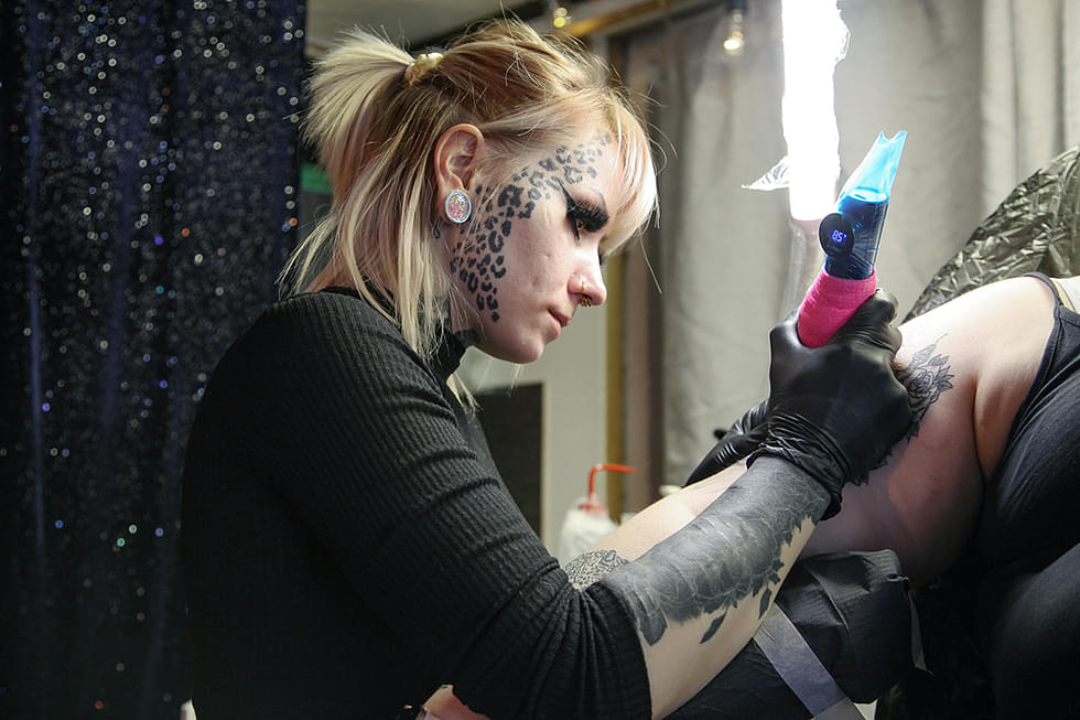 Mari Väänänen tekee peittotatuointia asiakkaan vanhan tatuoinnin päälle.