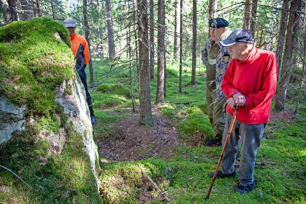 Maanomistaja Viljo Hirvonen (oik.) esittelee rahakiveä Eero Peltoselle ja Juha Koljoselle (kiven takana), jotka retkeilevät katsomassa Sarvingin muinaisia asuinsijoja.
