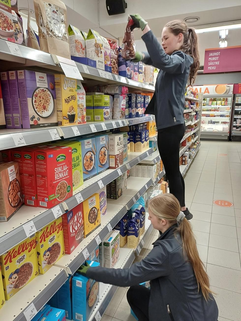 Anni-Mari Varis (takana) ja Eveliina Kiiski täyttivät hyllyjä Enon K-marketissa.