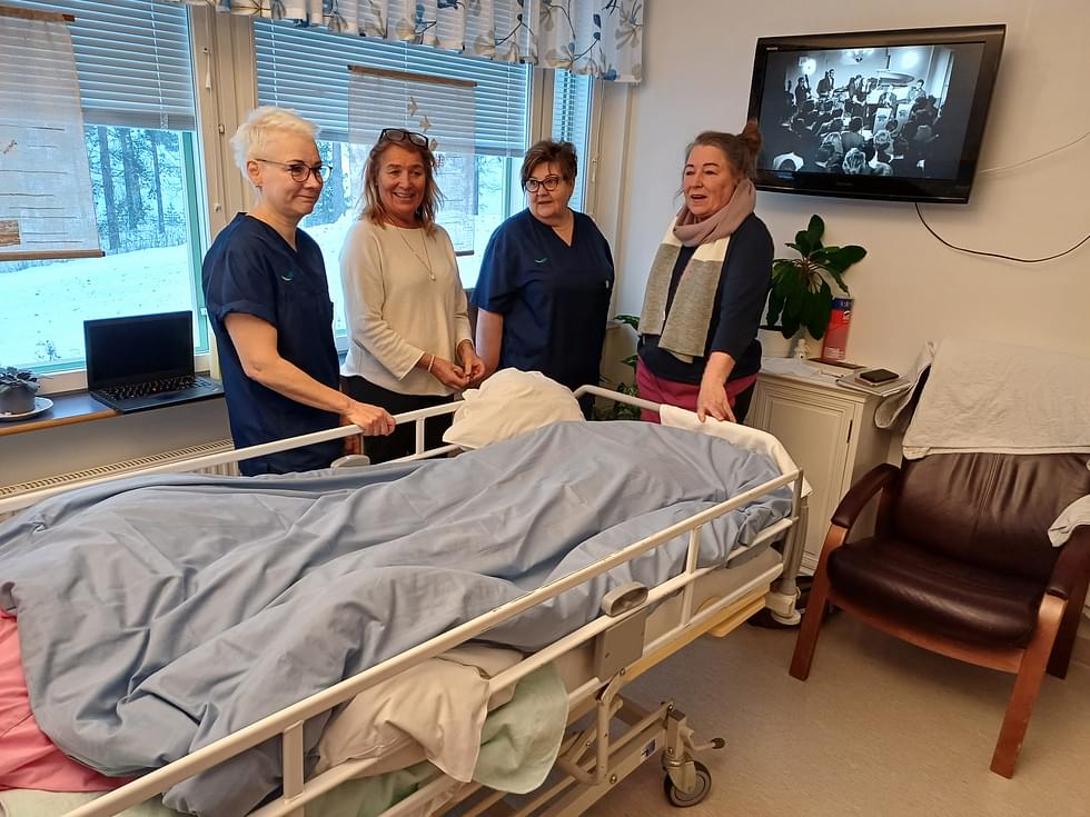 Marjut Kuokkanen (oik.) ja Jaana Kuokkanen-Björk (2. vas.) äitinsä saattohoitohuoneessa Parikkalan hyvinvointikeskuksen sairaalassa, jossa saattohoidosta vastaavat Pirjo Innanen (vas.) ja Kaija Makkonen. 