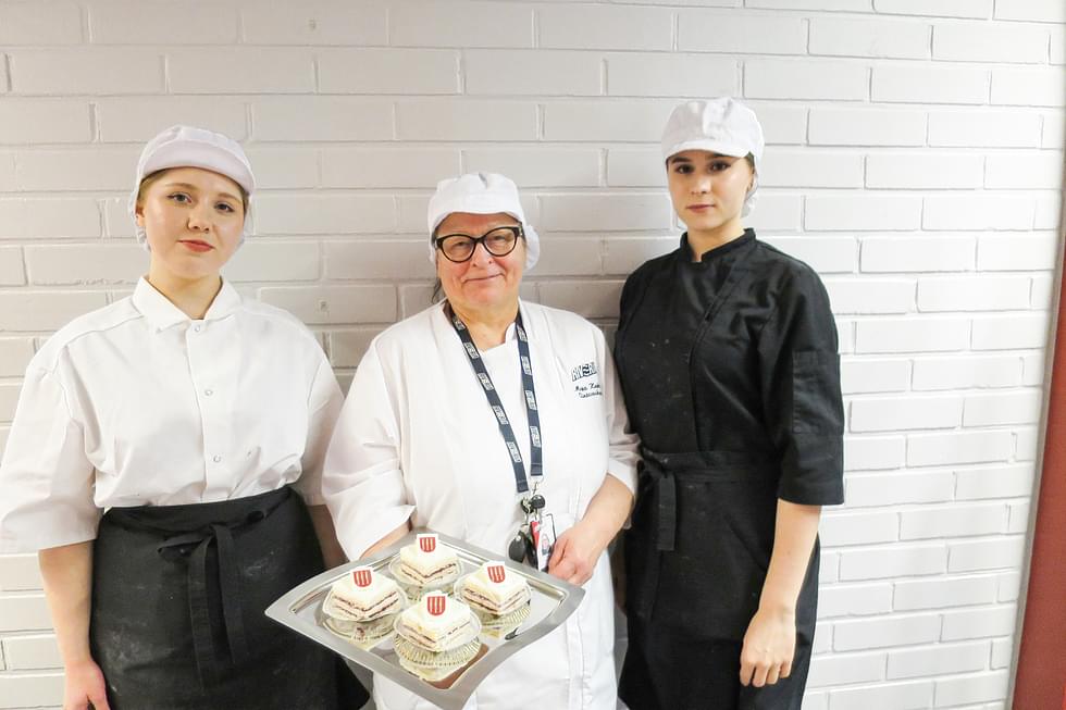 Adelina Feshchenko (vas.), Mirja Keskinen ja Viktoriia Kauranen esittelevät Nurmeksen vaakunalla koristellut juhlaleivokset.